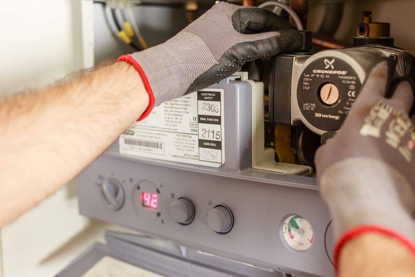 Servicetechniker arbeitet an einer Gastherme mit Umwälzpumpe